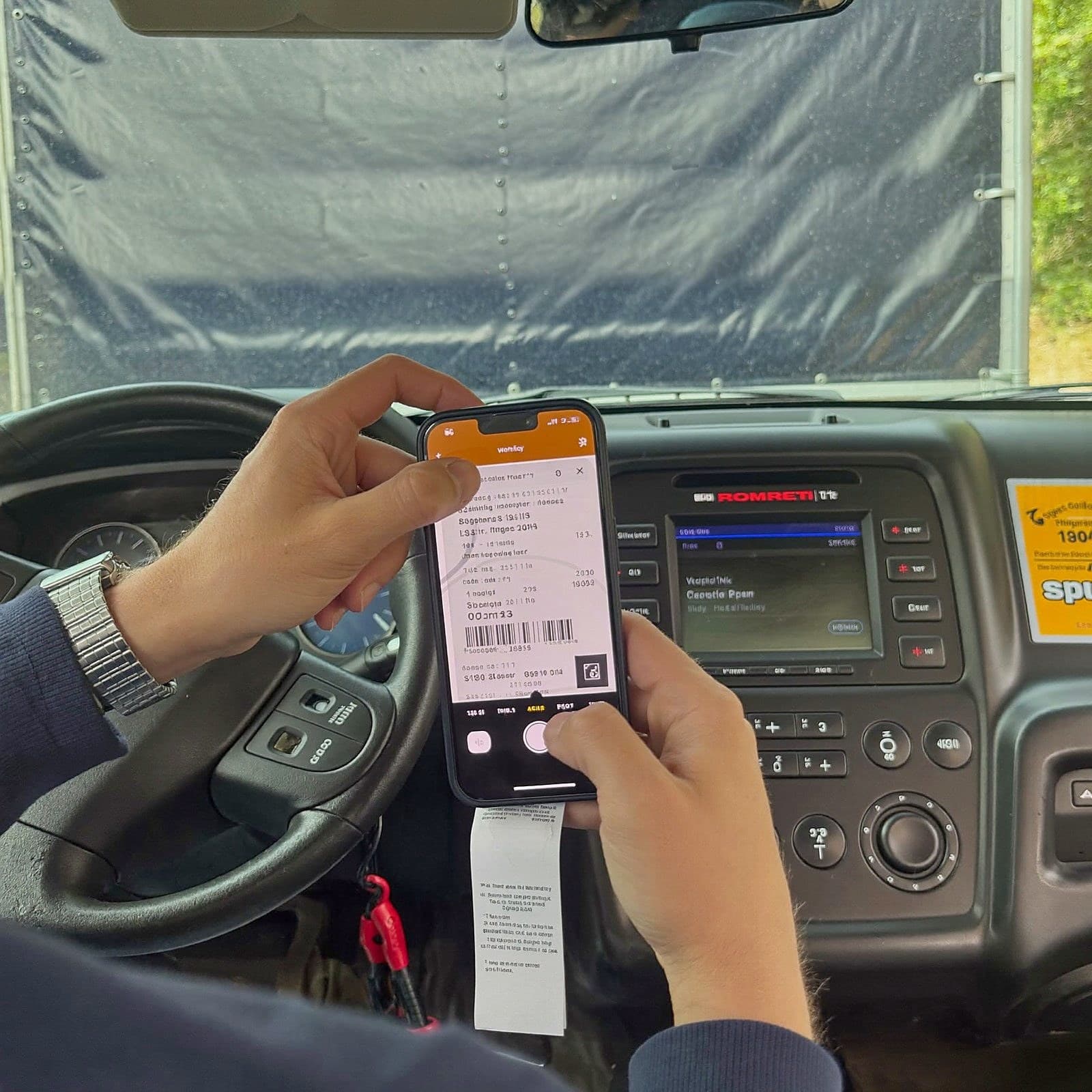 Driver capturing a fuel receipt with a phone inside the cab