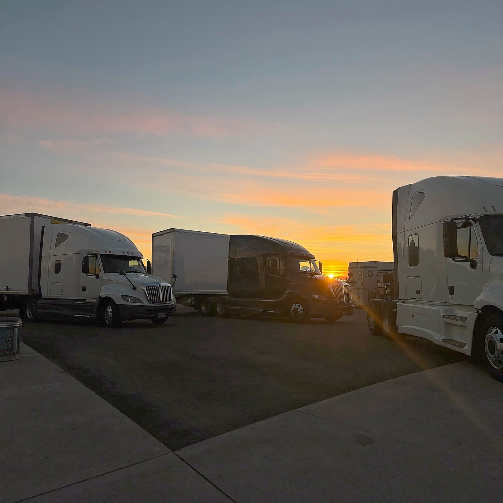 Semi-trucks lined up at a truck stop at golden hour